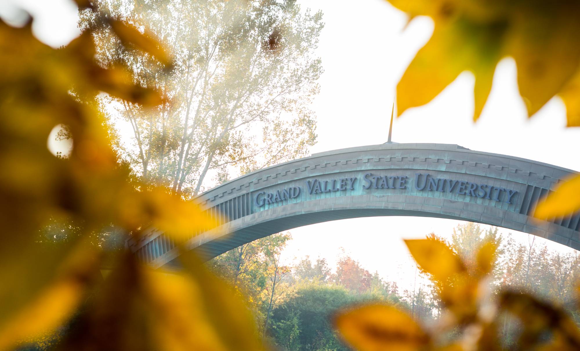 GVSU Entrance Arch in the early morning with fall leaves around it